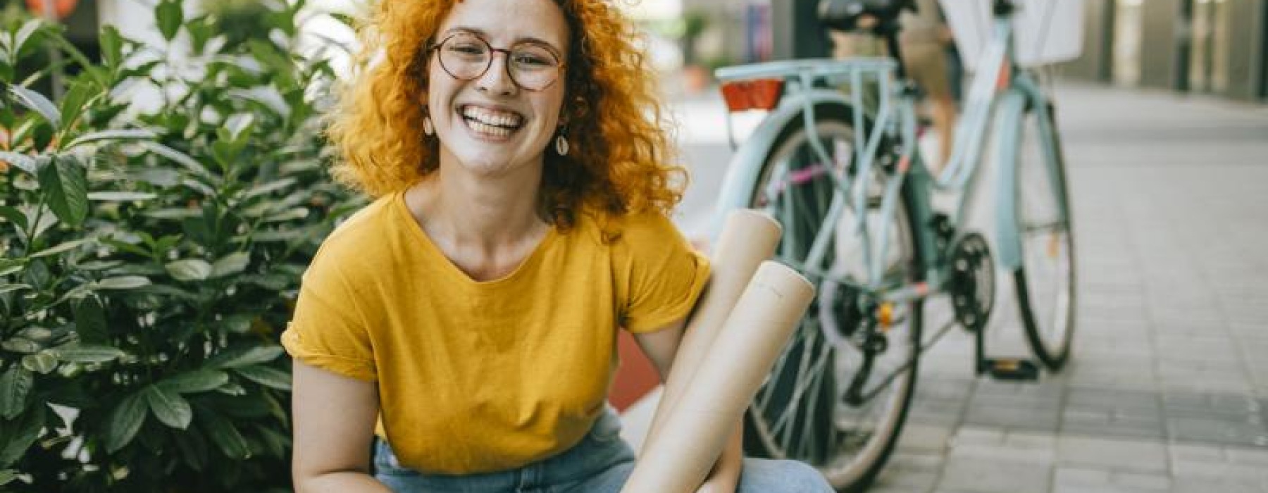 woman sitting on a sidewalk next to a bicycle