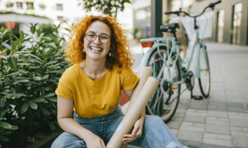 woman sitting on a sidewalk next to a bicycle