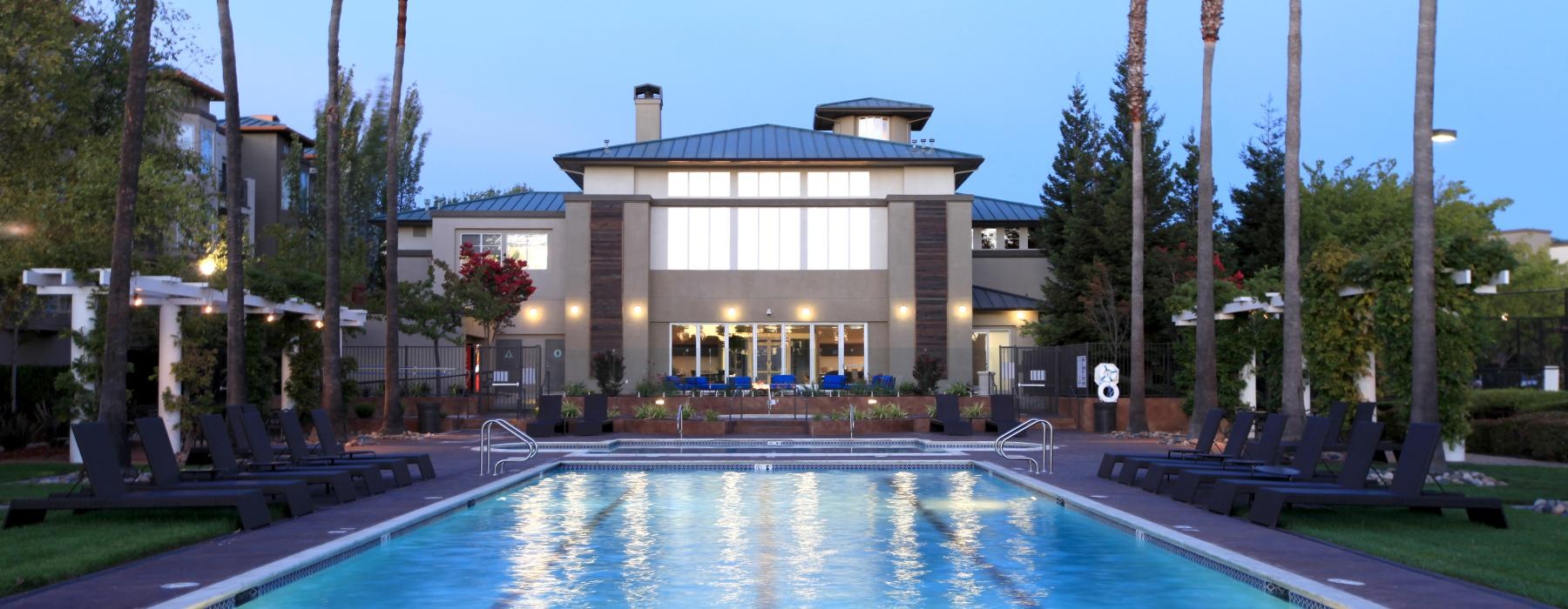 a swimming pool in front of clubhouse with palm trees