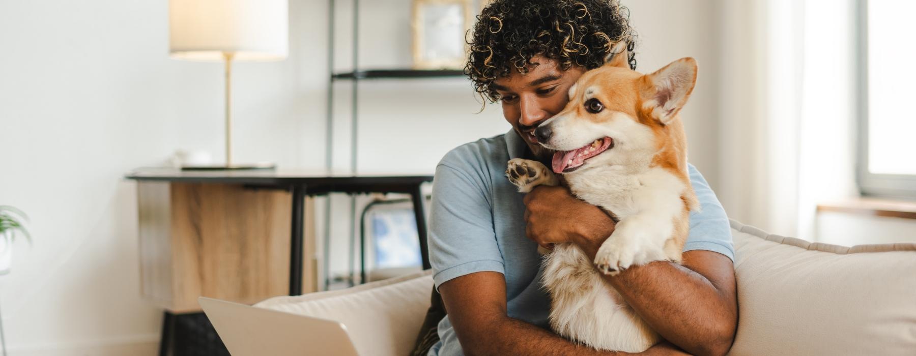 man and a dog on a couch with a laptop